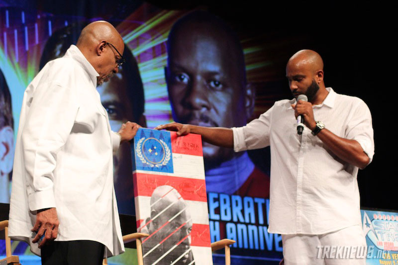 Cirroc Lofton presents Avery Brooks with a piece of art