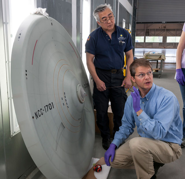 Engen Conservation Chair Malcolm Collum and Will Lee discuss the markings on the bottom of the saucer section before the model is reassembled.